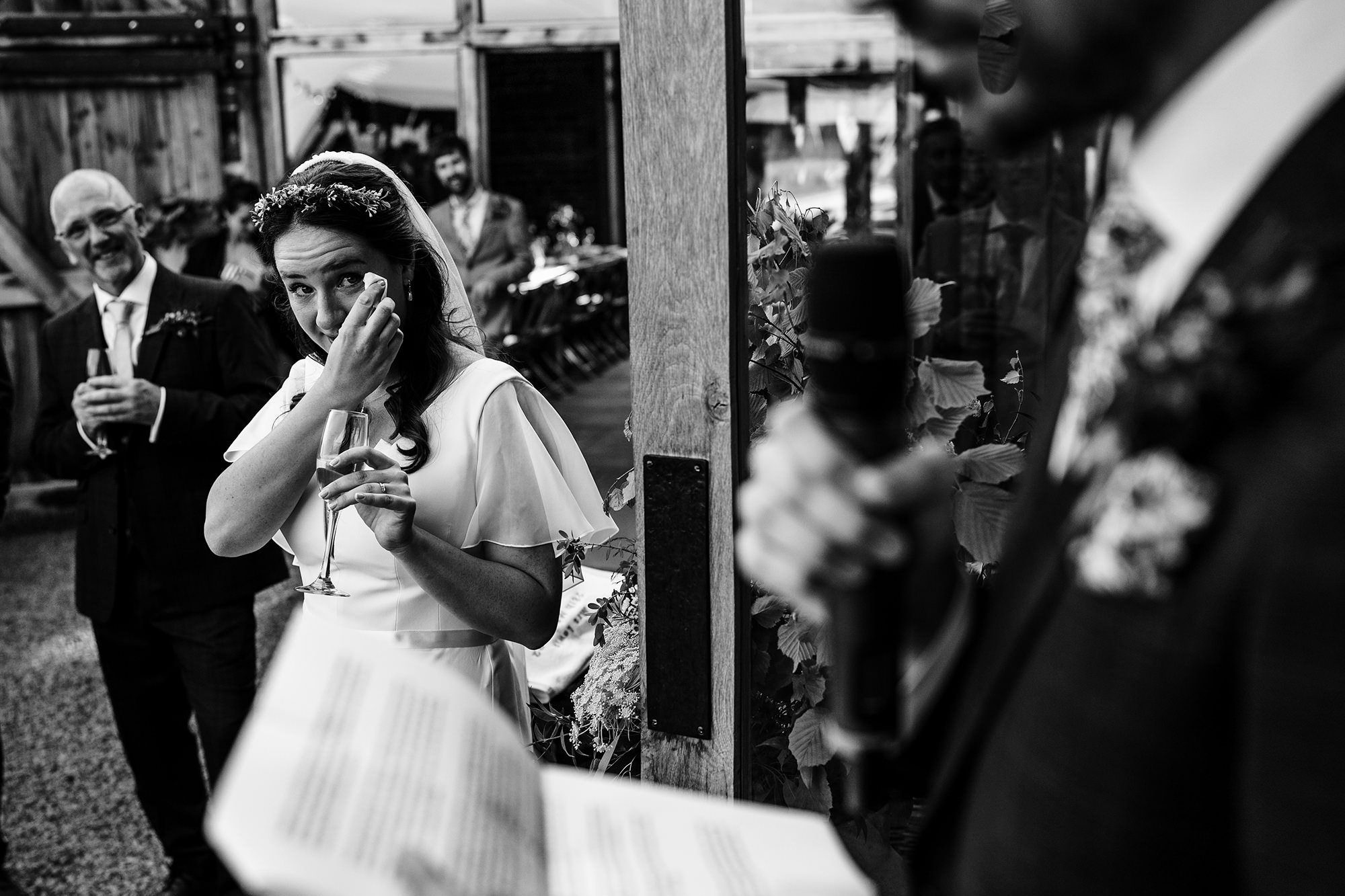 emotional bride wipes her tear watching the groom give his speech