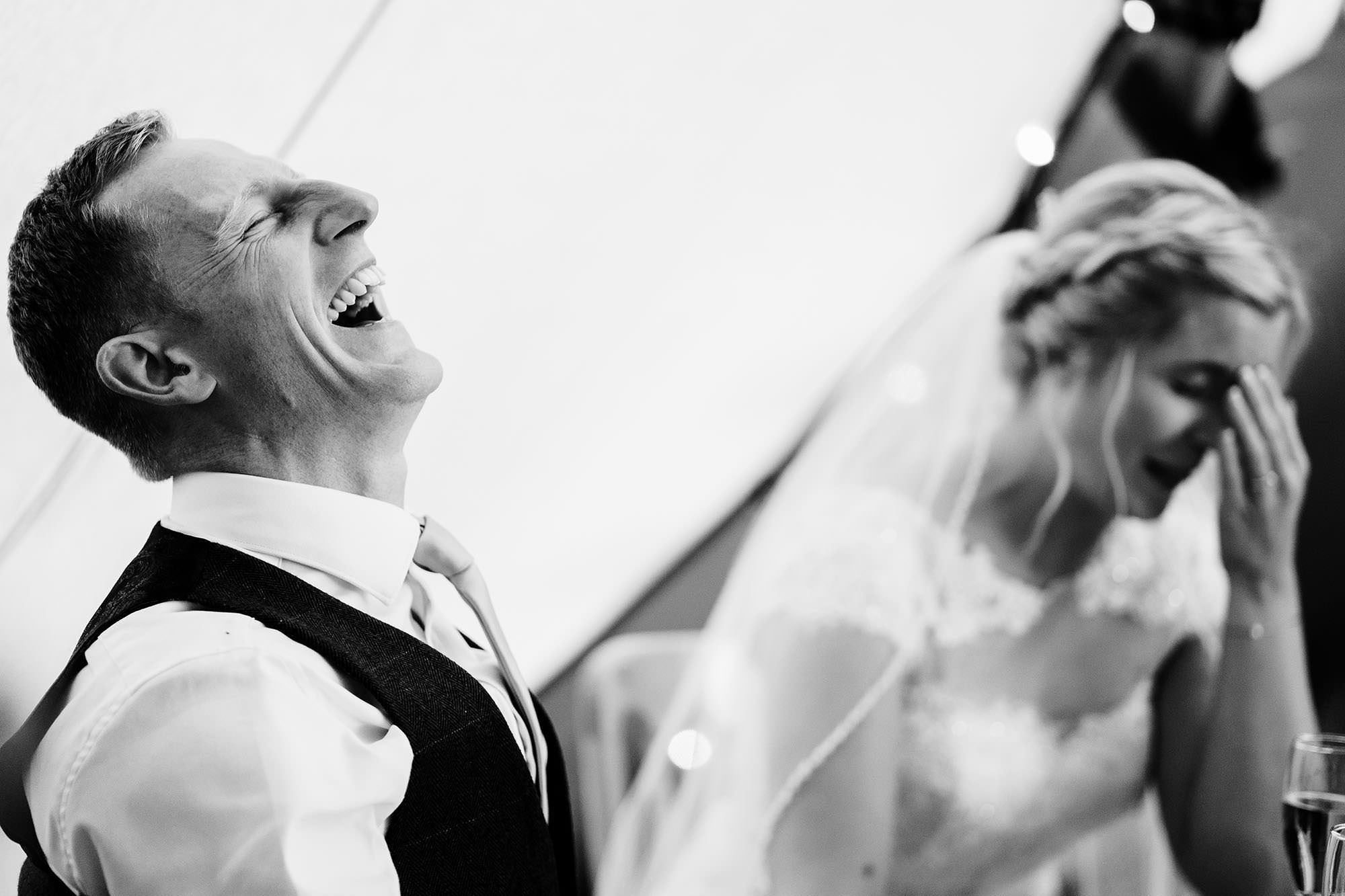 groom laughs during speeches in a cotswolds wedding photo